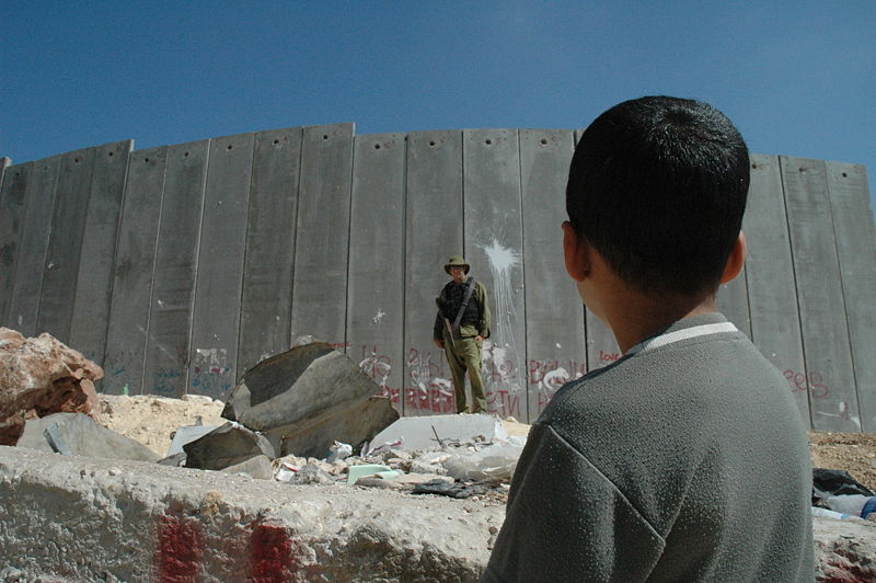 Boy and soldier in front of Israeli wall